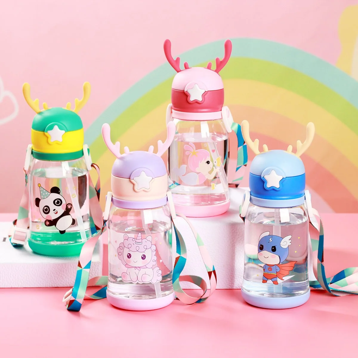 Four cartoon printed sipper water bottles in green, pink, purple and blue with antler-shaped lids and carry straps